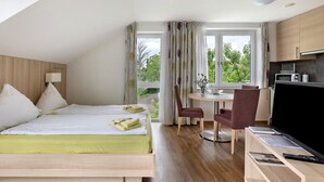 Een hotelkamer met een bed, een bureau met stoel, een televisie en een raam met gordijnen.