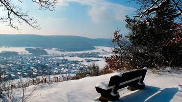 A bench on a snowy hill overlooking a town.