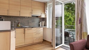A modern kitchen with wooden cabinets, a built-in oven, and a large sliding glass door leading to a balcony. - Holiday Apartment 'Trollinger' with Kitchenette, Balcony, and Wi-Fi (Vaihingen an der Enz)