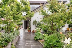 A garden pathway leading to a building with a tiled roof and a door. - Holiday Apartment 'Trollinger' with Kitchenette, Balcony and Wi-Fi (Vaihingen an der Enz)