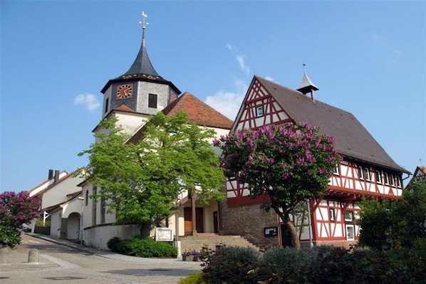 Un bâtiment traditionnel à colombages, doté d’un clocher, d’une église et d’un jardin bien entretenu.
