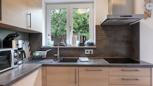 A modern kitchen with a built-in oven, microwave, and coffee maker. - Apartment 'Burgunder' with Private Terrace, Kitchenette and Wi-Fi (Vaihingen an der Enz)