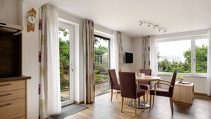 A modern room with a dining area, a TV, and a view of the outdoors. - Apartment 'Burgunder' with Private Terrace, Kitchenette and Wi-Fi (Vaihingen an der Enz)