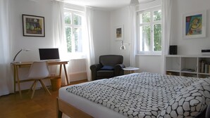A bedroom with a bed, a desk with a computer, a chair, a radiator, and a bookshelf. - Holiday Home 'Schlößleweg 2a' with Private Terrace, Private Garden and Wi-Fi (Bodman-Ludwigshafen)