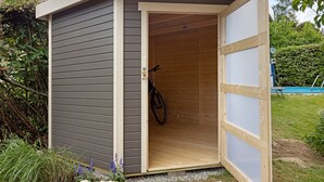 A small wooden shed with a partially open door, revealing a bicycle inside. - Lovingly Furnished Holiday Apartment in Gaienhofen on Lake Constance (Gaienhofen)