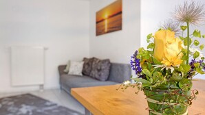 A living room with a sofa, a coffee table, and a vase with flowers. - Lovingly Furnished Holiday Apartment in Gaienhofen on Lake Constance (Gaienhofen)