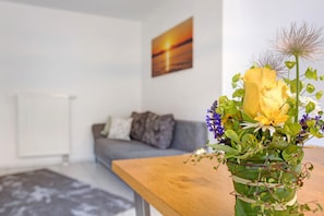 A living room with a sofa, a coffee table, and a vase with flowers. - Holiday Apartment 'Bruttel' with Private Pool, Shared Terrace and Wi-Fi (Gaienhofen)