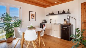 Een moderne keuken met houten balken, een eettafel met stoelen, een koffieapparaat en een vaatwasser.