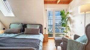 Een slaapkamer met een bed, een stoel, een lamp, een plant en uitzicht door een raam.