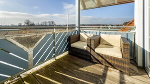 Een balkon met rieten meubilair en uitzicht op een ver landschap.