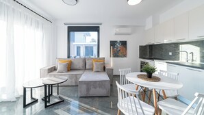 Een moderne woonkamer met een bank, een salontafel en een eethoek met stoelen en een kleine tafel.