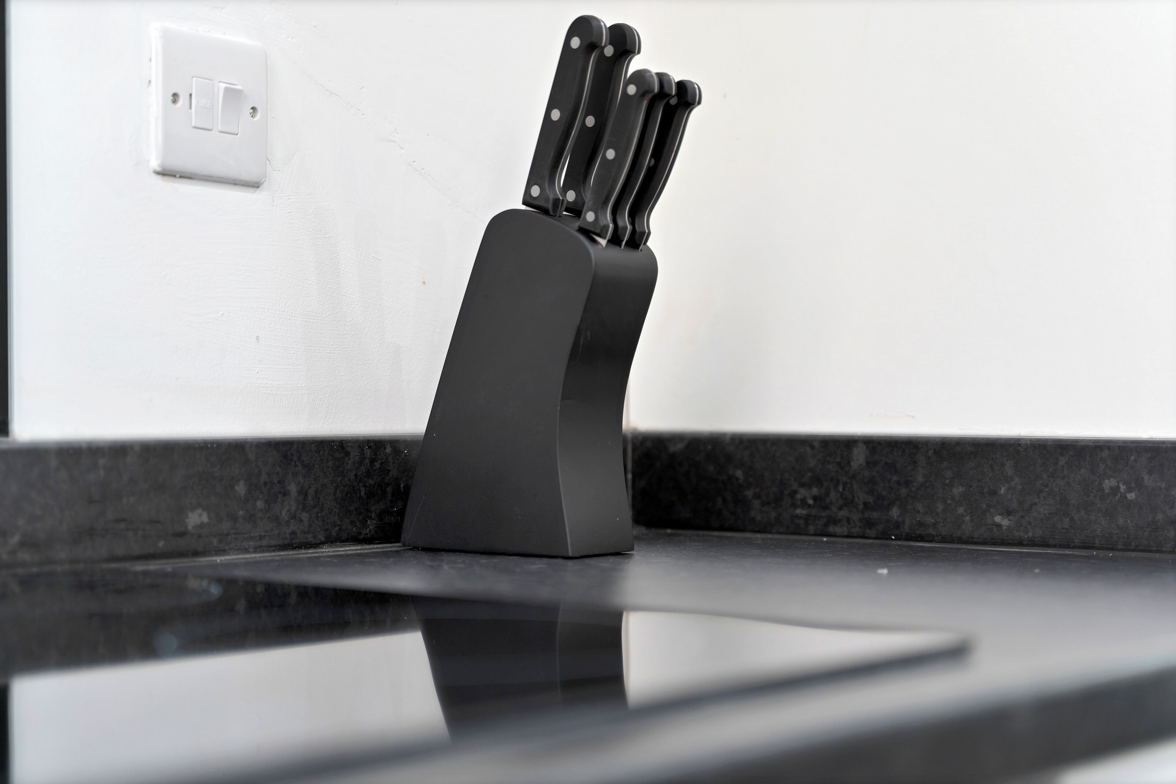 A black knife block with knives on a countertop.