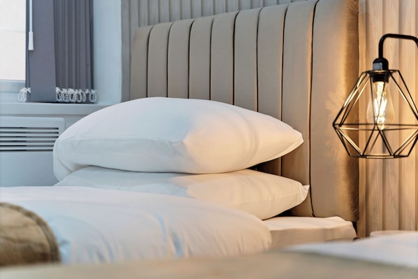Un lit bien fait, avec du linge de lit blanc et une tête de lit ornée de lignes verticales.