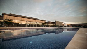 A modern building with a large glass facade and a swimming pool.
