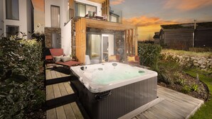 A modern house with a hot tub and outdoor seating area.