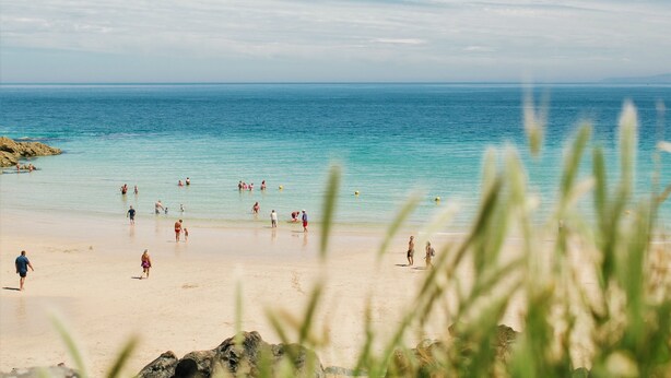 A beach with clear blue water and people enjoying the sand and water.