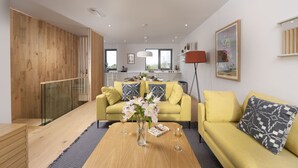 A modern living room with a yellow sofa, a wooden coffee table, and a vase with flowers.