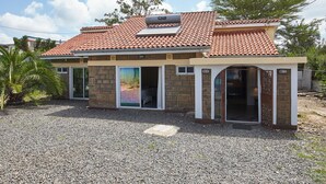 A two-story house with a tiled roof, a front door, and a large sliding glass door. - JKIA Boutique Inn (Syokimau)