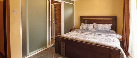A bedroom with a wooden bed, a sliding glass door closet, and a tiled floor.