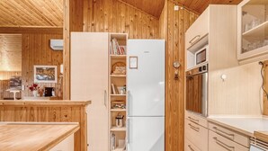 Eine kleine Küche mit Holzschränken, einem weißen Kühlschrank, einem Herd und einer Mikrowelle.