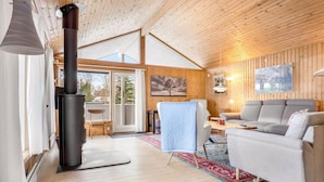 Ein gemütliches Blockhauss-Interieur mit Kamin, Holzwänden, einer Couch und einer Essecke.
