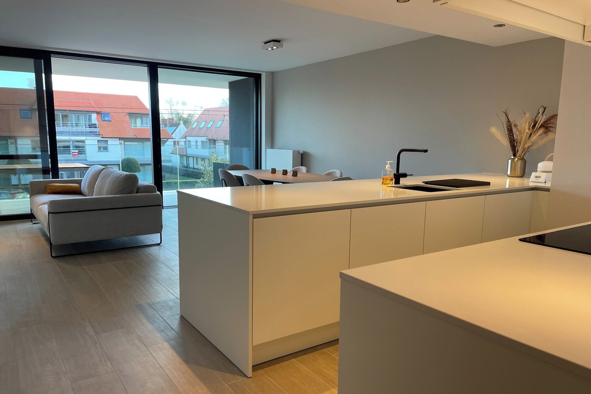 A modern kitchen with a large island, a sofa, and a view of the city.