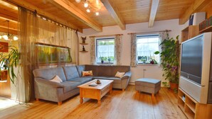 A cozy living room with a grey sofa, wooden coffee table, and a flat-screen TV. - Chalet in Einach near Ski Slopes (Stadl an der Mur)
