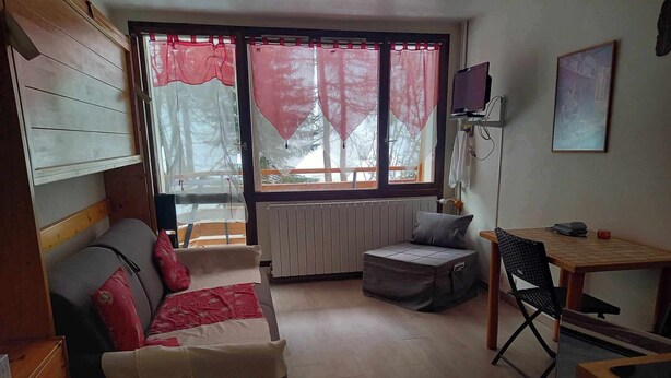 A compact living space with a sofa, a small table, a chair, and a radiator.