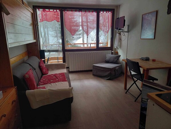 Un espacio habitable pequeño con un sofá, una mesita, una silla y un radiador.