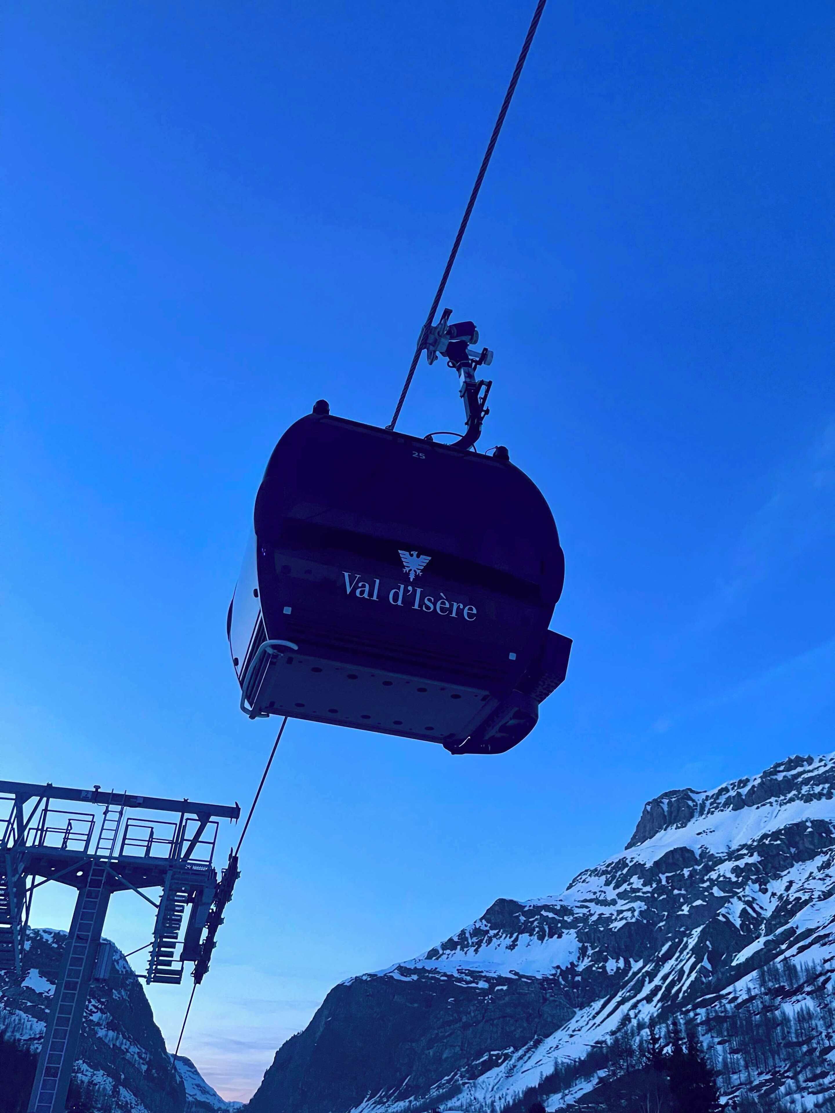 «Val d’Isère» -nimellä varustettu köysirata, joka kulkee vuoristomaiseman yllä.
