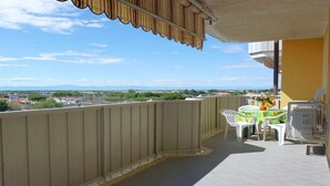 Ein Balkon mit Blick auf eine Stadtlandschaft, einem Tisch mit Stühlen und einem Vogelkäfig.