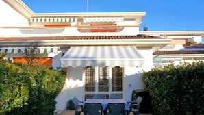 Un patio con una mesa y sillas, rodeado de follaje.