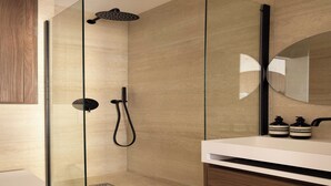 A modern bathroom with a glass-enclosed shower, a white sink, and a wooden vanity. - Charming Studio - 2P- Madeleine (Paris)