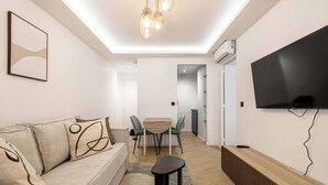 Una sala de estar moderna con un sofá, una mesita y un televisor montado en la pared.