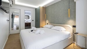 Una habitación de hotel moderna con una cama grande, un espejo, un panel de pared de madera y una lámpara colgante.