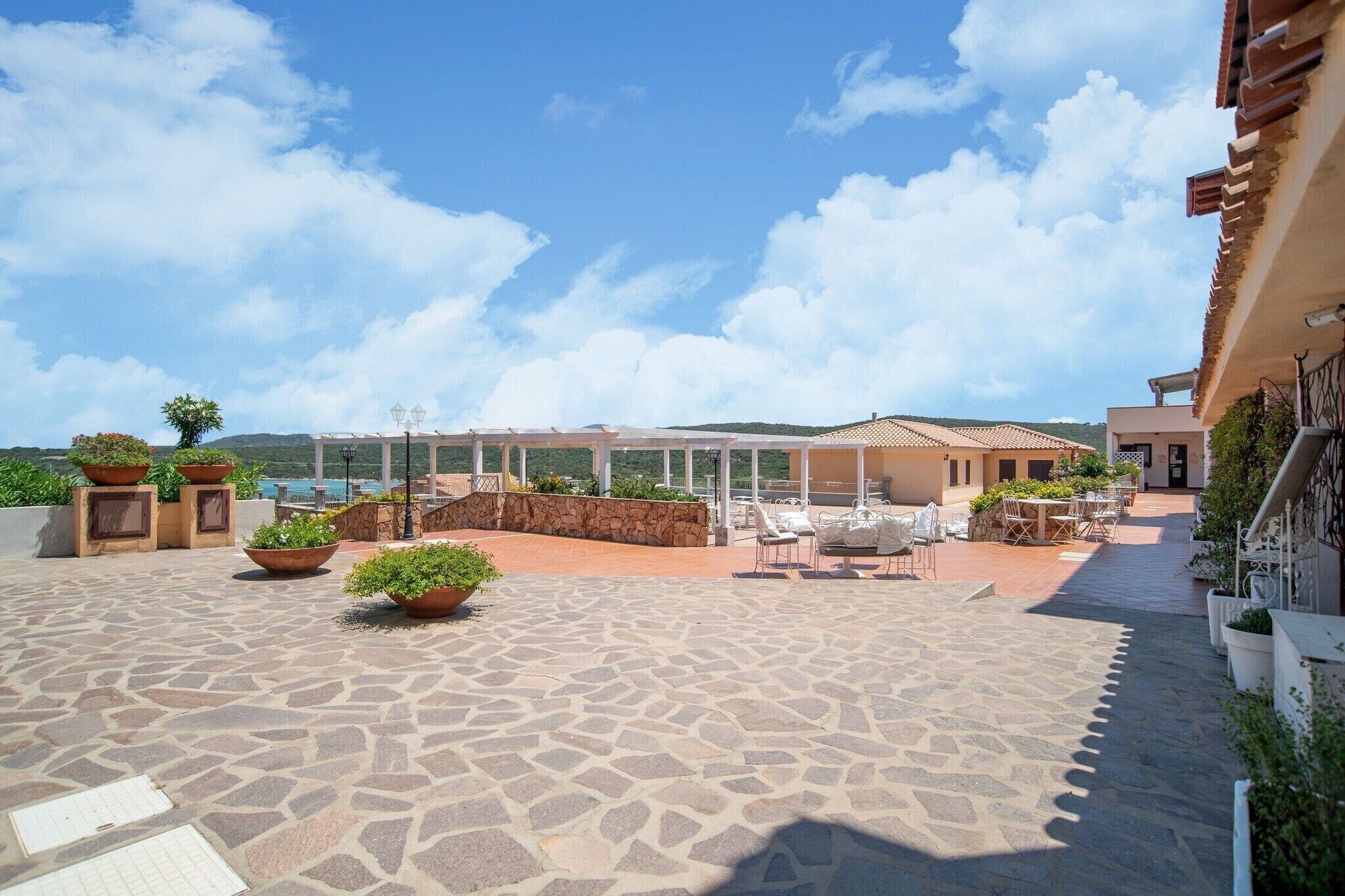A spacious outdoor patio with stone flooring, potted plants, and outdoor seating.