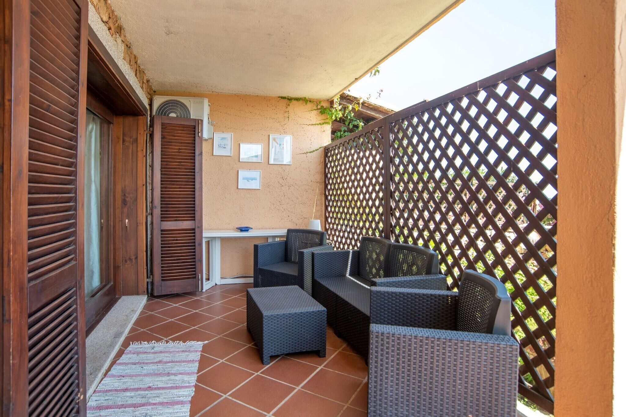 A patio with wicker furniture, a table, and a wall-mounted air conditioner.