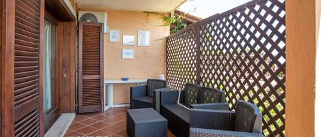 A patio with wicker furniture, a table, and a wall-mounted air conditioner.