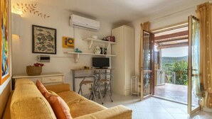 A cozy living room with a sofa, a TV, and a balcony with a view. - Apartment in Marinella near the beach (Marinella)