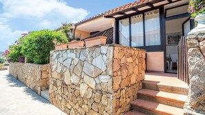 A stone wall with steps leading to a building with a tiled roof and large windows. - Apartment in Porto Rotondo near Beaches (Marinella)