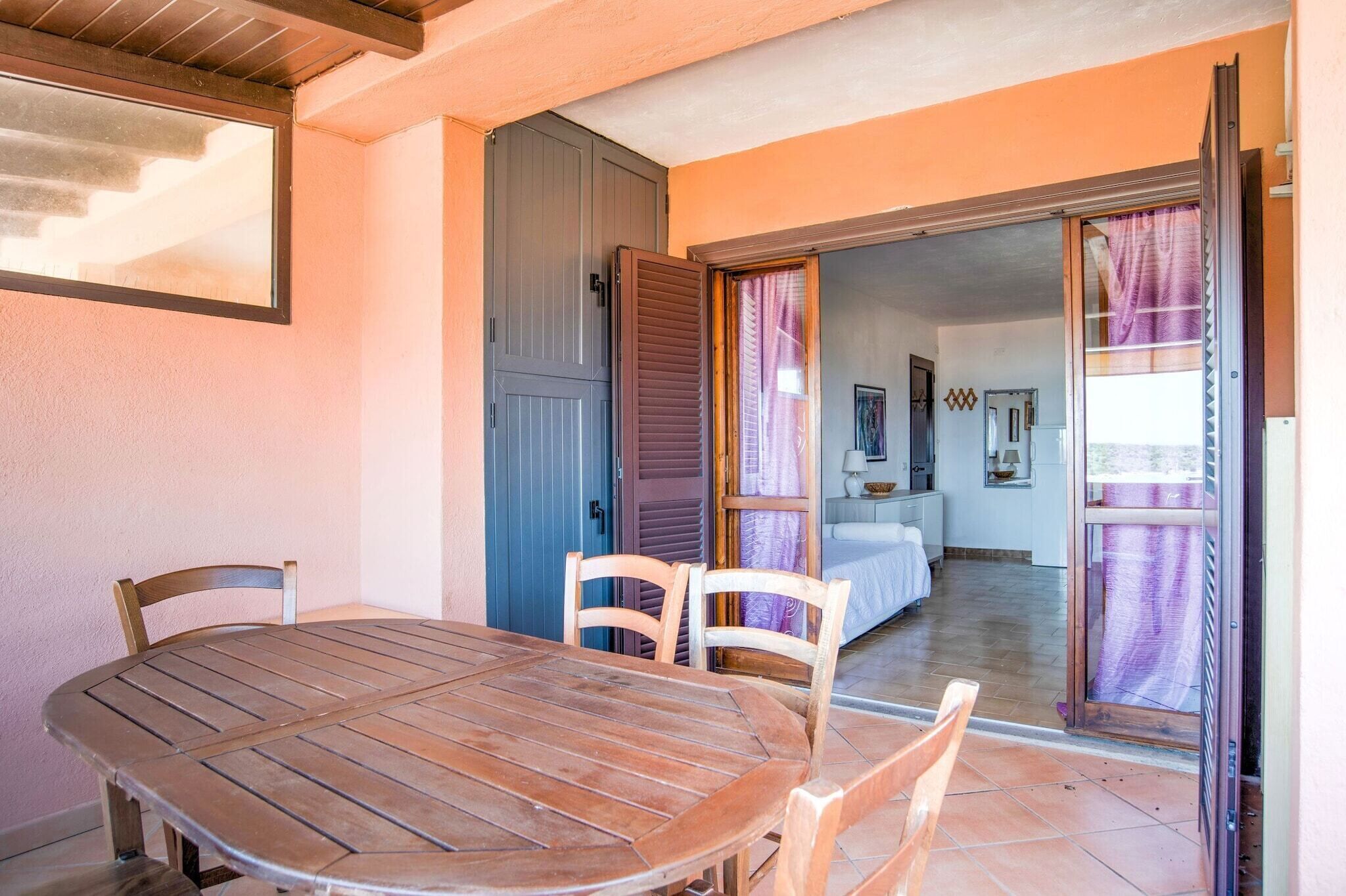 Un tavolo e delle sedie in legno in una stanza con una porta scorrevole che dà su una camera da letto.