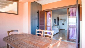 A wooden table and chairs in a room with a sliding door leading to a bedroom. - Apartment in Porto Rotondo near Beaches (Marinella)