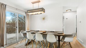 A modern dining area with a large table, white chairs, and a unique wall decoration. - Modern Family Friendly Escape|Central|5-Bedroom (Denver)