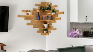 A modern kitchen with a wooden shelf unit displaying various decorative items and a neon sign. - Modern Family Friendly Escape|Central|5-Bedroom (Denver)