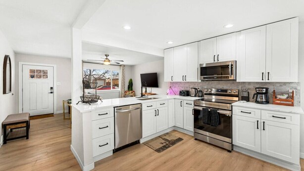 A modern kitchen with white cabinets, stainless steel appliances, and a wooden floor. - Modern Family Friendly Escape|Central|5-Bedroom (Denver)
