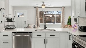 A modern kitchen with white cabinets, a stainless steel dishwasher, and a built-in oven. - Modern Family Friendly Escape|Central|5-Bedroom (Denver)