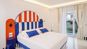A modern hotel room with a large bed, a curved headboard, and a view of the outside balcony. - Pepella (Piano di Sorrento)