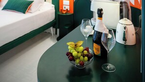 A hotel room with a bed, a table with a bottle of wine, glasses, and a bowl of fruit. - Pepella (Piano di Sorrento)