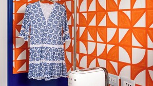 A room with a blue and orange geometric wall pattern, a white toaster, two white cups, and a hanging garment. - Pepella (Piano di Sorrento)