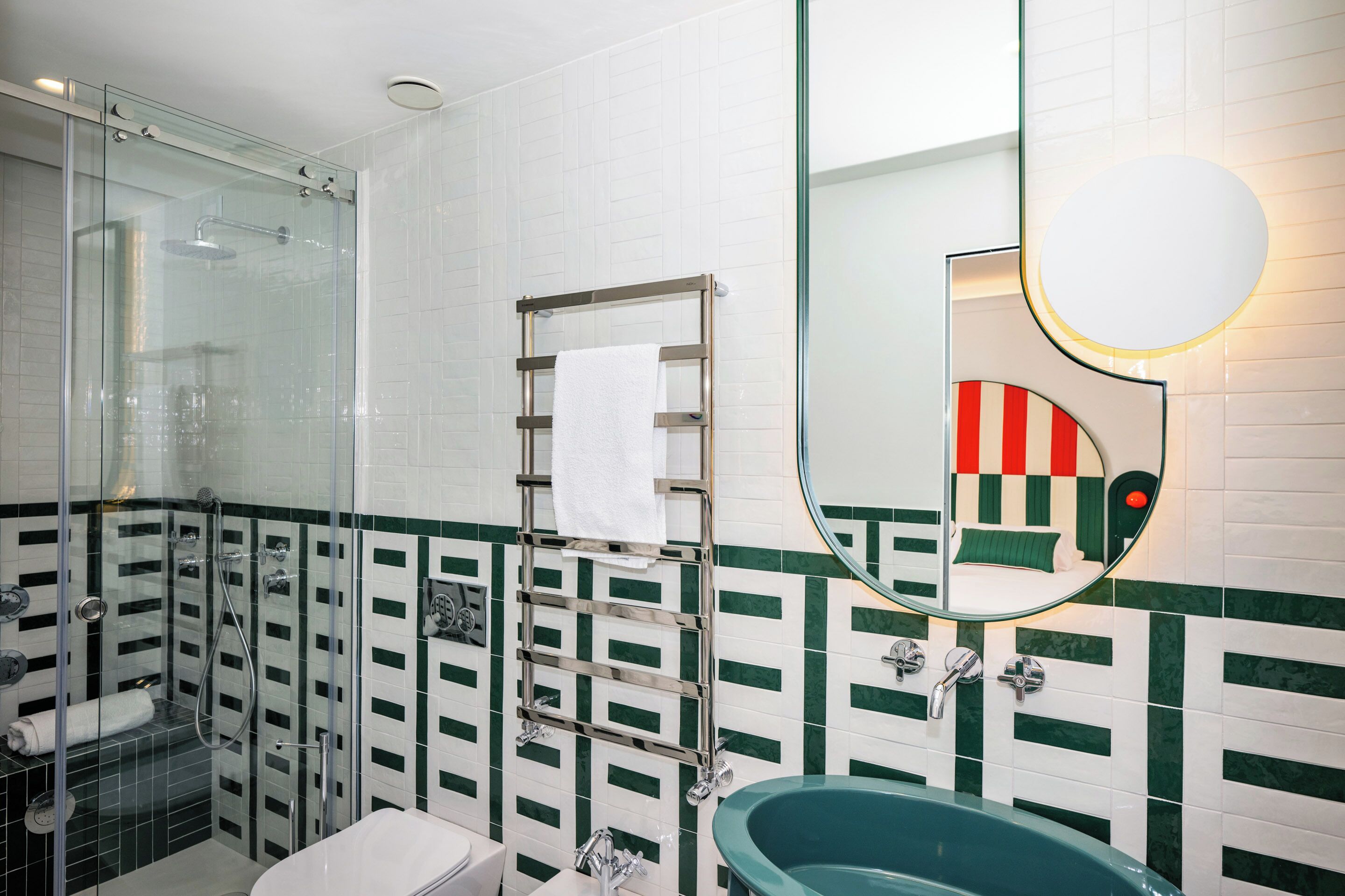 Ein modernes Badezimmer mit einer Duschkabine aus Glas, einer freistehenden Badewanne und einem großen Spiegel mit runder Rahmung.